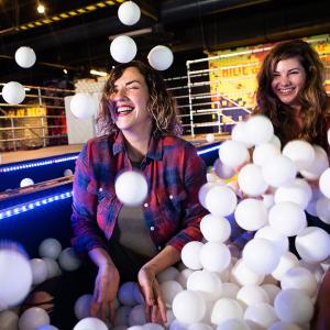 Two women playing in a white ball pit