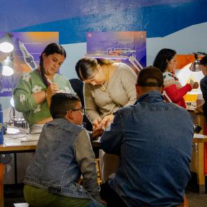 A family gathered around a work bench focused on doing crafts