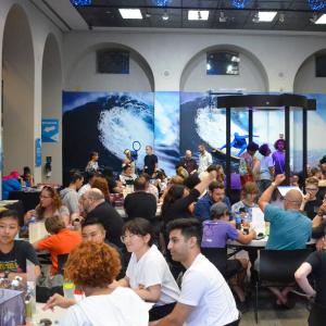 A crowded room with people of all ages sitting at different tables playing games
