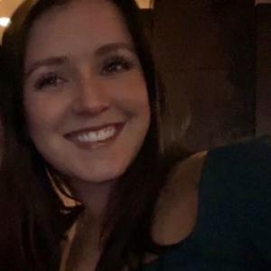 A dark lit selfie of a young smiling woman 