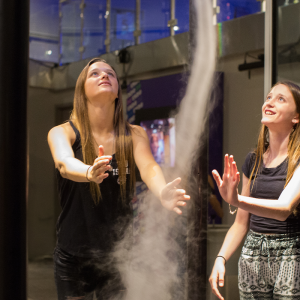 Two teen girls interacting with an indoor tornado