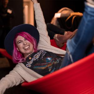 A woman in a tipping round chair sticking her tongue out at the camera 