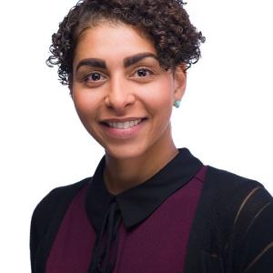 A darker skinned woman with short hair in a black and maroon shirt 