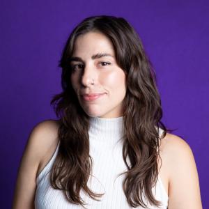 A hispanic woman in a white top against a purple background