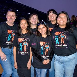 A group of women and two girls wearing matching shirts and smiling