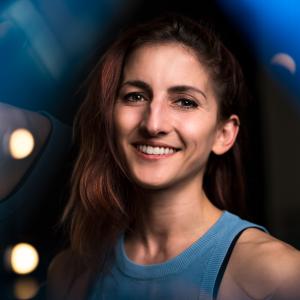 A woman with a bright smile, wearing a blue tank top, conveying a sense of joy and friendliness.